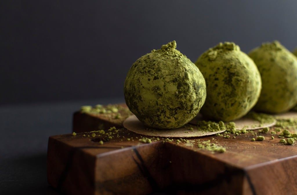 Trufas cobertas com pó verde sobre tábua de madeira em close-up