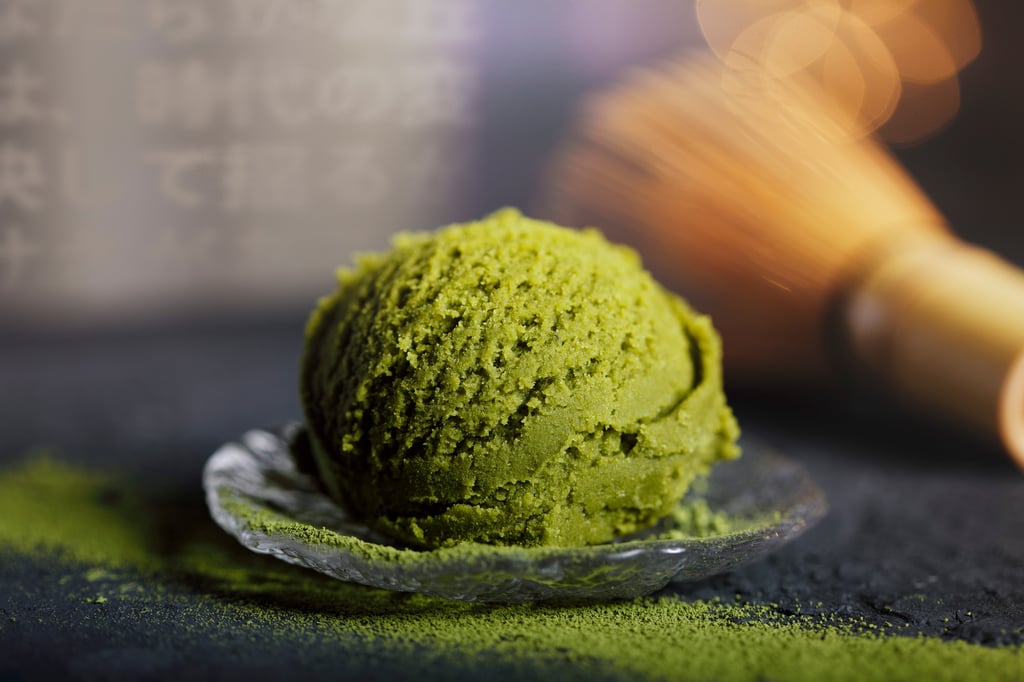 Bola de sorvete verde servida em recipiente de vidro sobre superfície escura