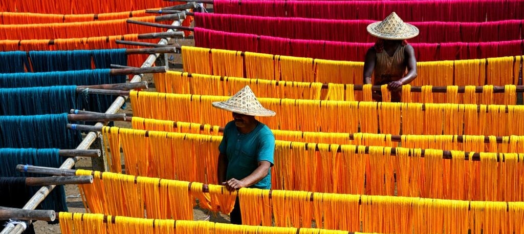 Trabajadores en proceso de teñido y secado de hilos textiles de colores, representando el impacto real en cadenas de suministro más sostenibles.