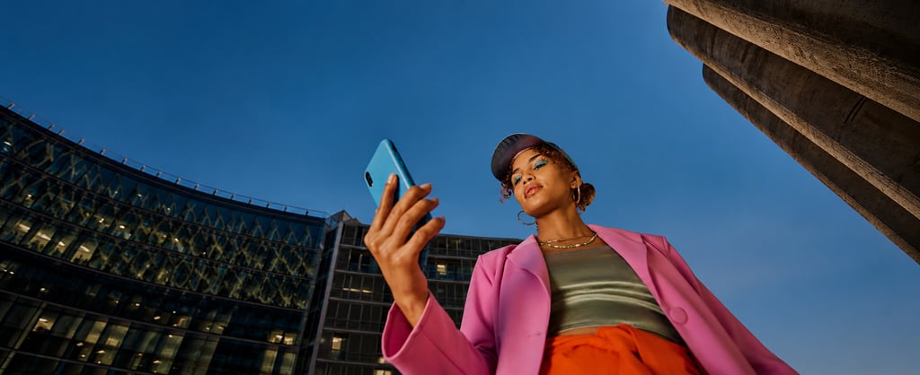 Woman using a smartphone outdoors in a modern city setting.