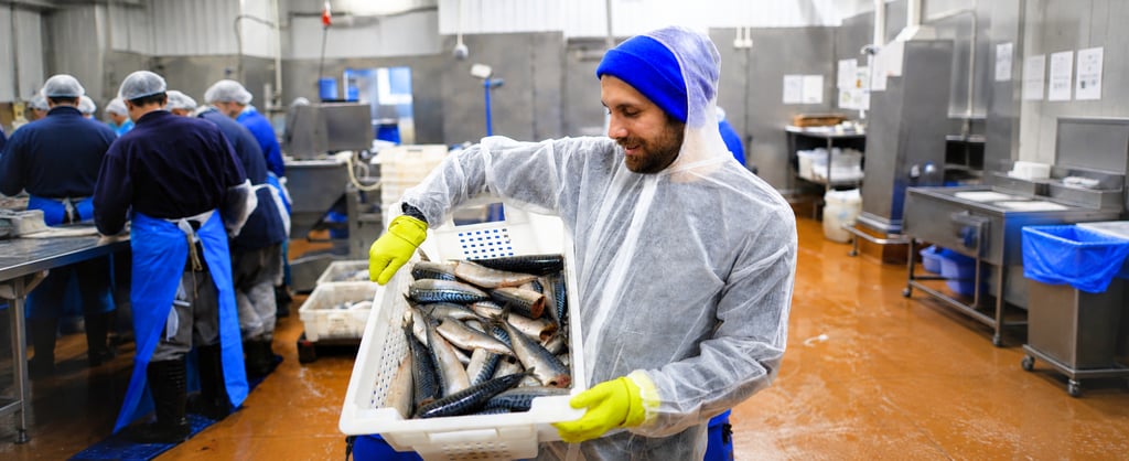 Men working in background and a man holding a box of fishes
