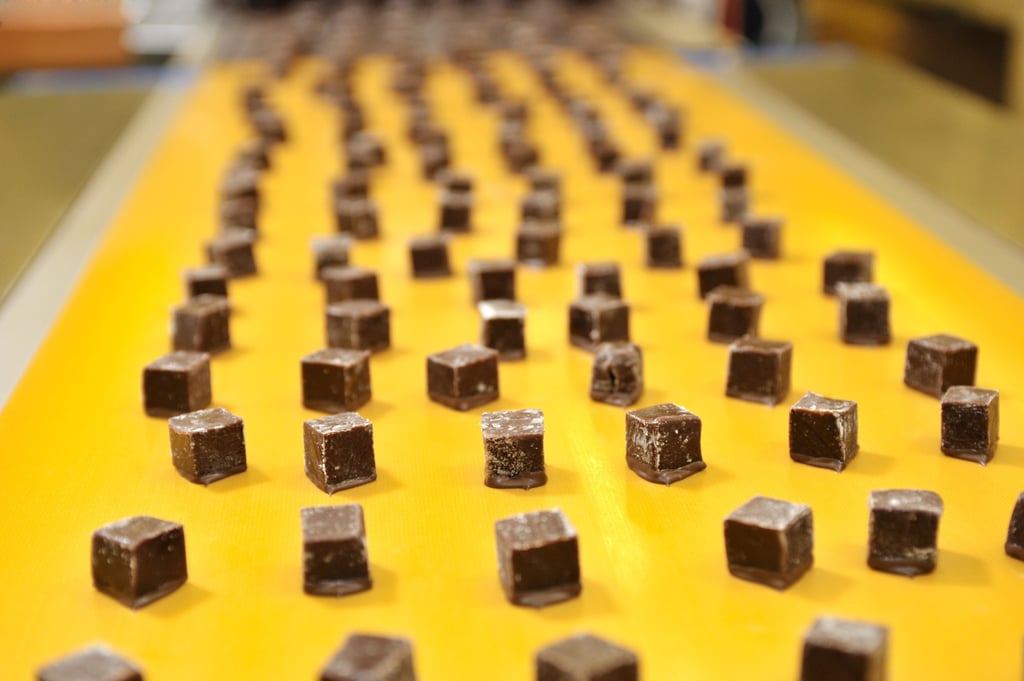 Cubos de chocolate avanzando sobre una línea de producción, representando la transición a FSSC 22000 Versión 7 y la gestión de la inocuidad alimentaria.