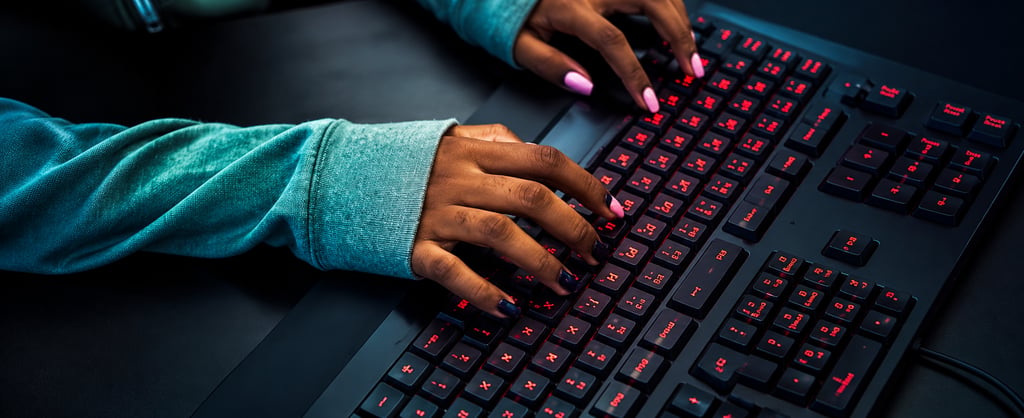 A woman with pink nails typing on black keyboard that is flashing red on the letters