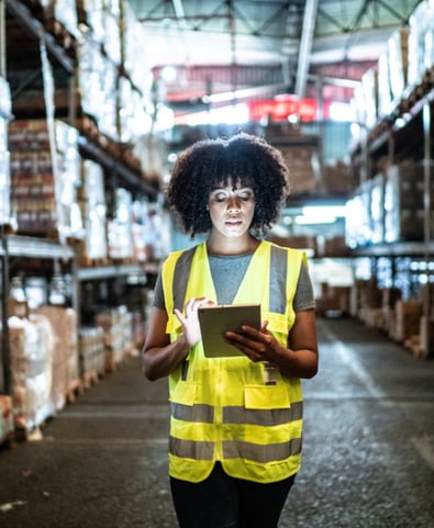 Woman in yellow high vis in the factory, looking at her ipad
