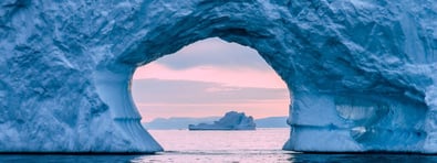 View through a natural ice cave overlooking the ocean at sunrise, symbolising transparency, perspective and resilience.