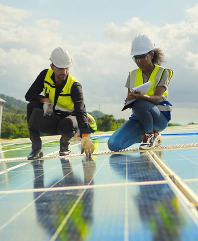 2 workers in yellow high vis jackets inspecting solar panels