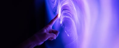 Hand touching a glowing digital display with purple and blue light effects