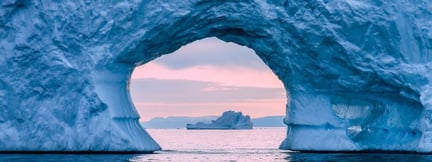 View through a natural ice cave overlooking the ocean at sunrise, symbolising transparency, perspective and resilience.