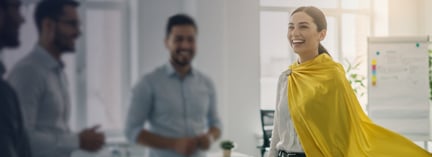 Businesswoman wearing a yellow cape in an office meeting.