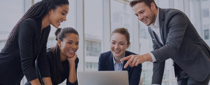 Business professionals collaborating around a laptop in a bright, modern office.
