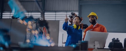 Two engineers in protective workwear reviewing equipment and monitoring operations in an industrial facility.
