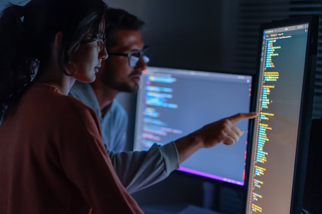 People looking at the code on a computer screen