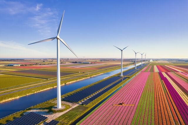 Wind turbines and solar panels alongside agricultural fields, representing renewable energy, sustainable development and climate action.