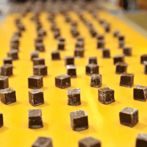 Cubos de chocolate en una línea de producción, representando la transición a FSSC 22000 Versión 7 y la inocuidad alimentaria.